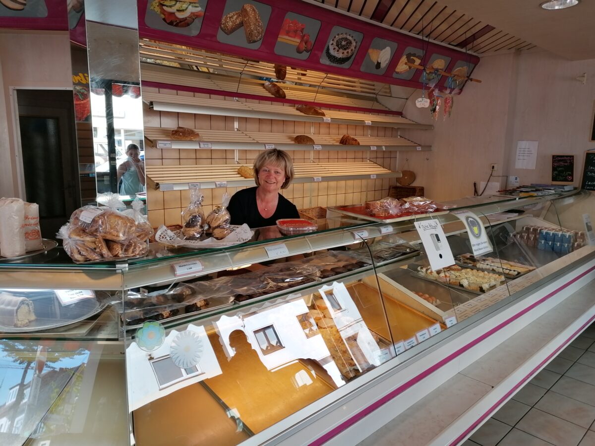 Eine Frau steht hinter dem Tresen in einem Bäckereigeschäft.